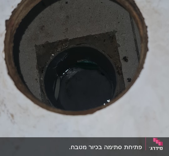 מבט לתוך פתח ניקוז וקופסת ביקורת ברצפה עם מים עומדים